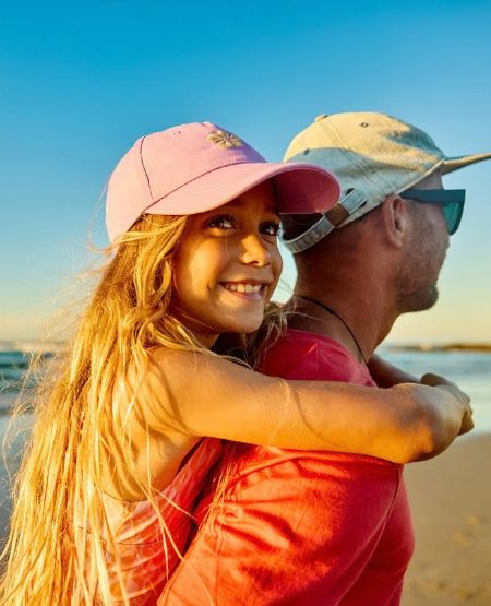 Far og datter på strand i Australien, klar til surfing