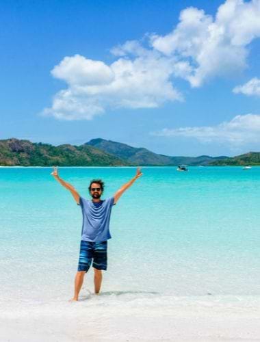 Glad mand på stranden på Whitehaven Beach, Australien Glad mand på stranden på Whitehaven Beach, Australien