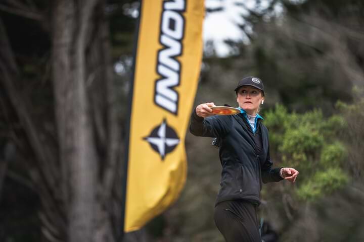 Holly Finley throwing in cold weather disc golf gear.
