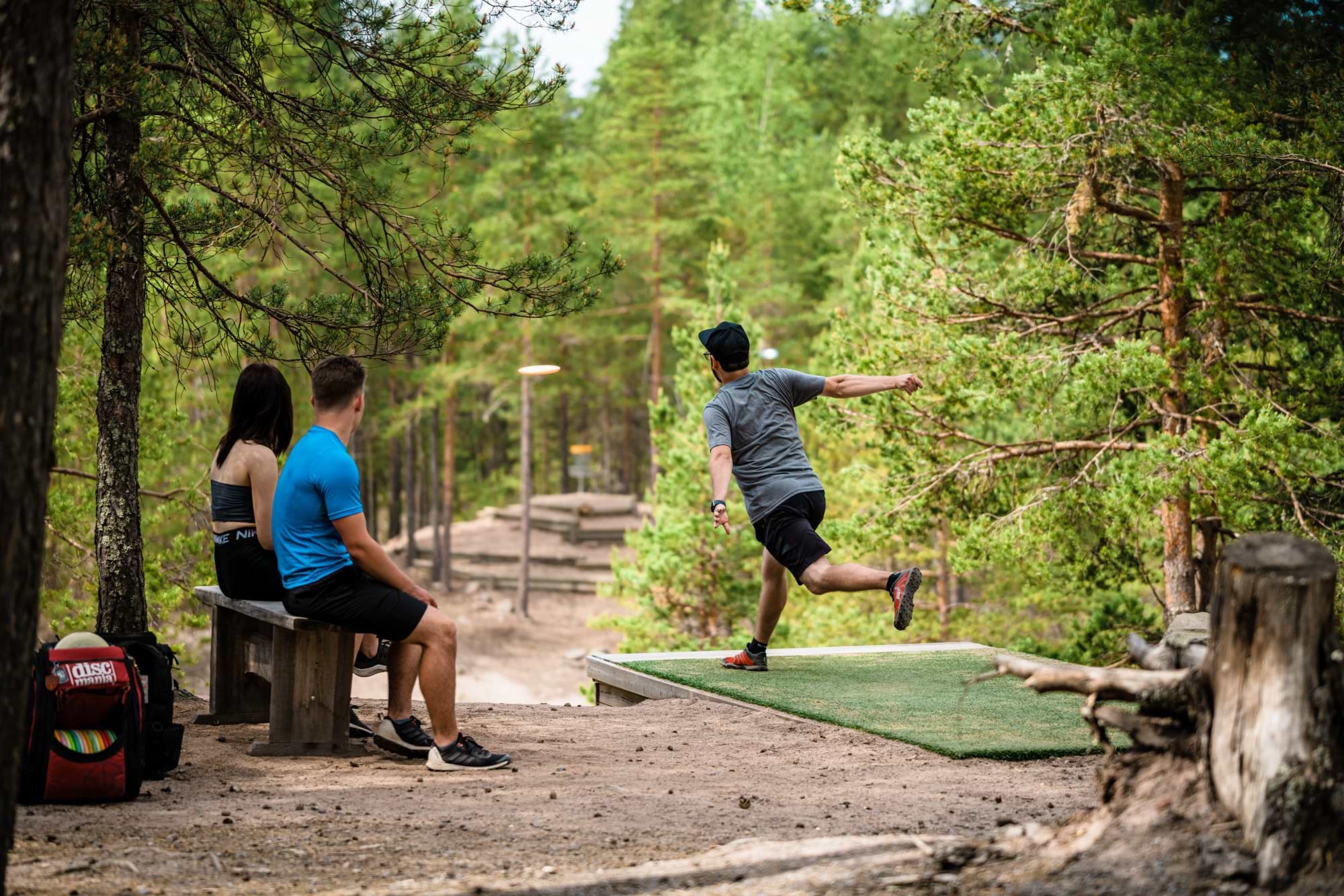 Disc Golfer teeing off as friends watch