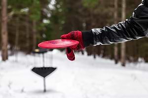 Winter disc golf. Player putting a disc in the snow.