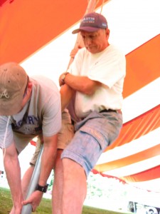 Tom lending his muscle to raise the red and white tent