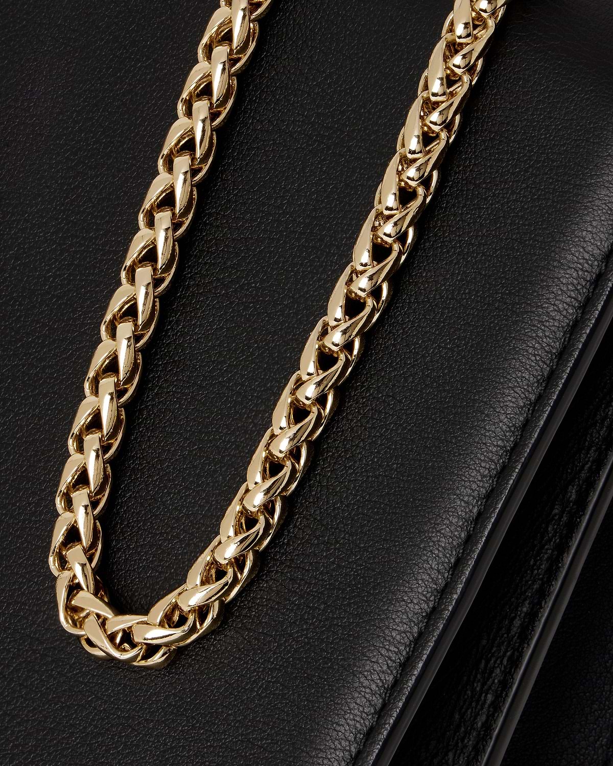Black east-west bag showing pebbled leather and gold chain strap.
