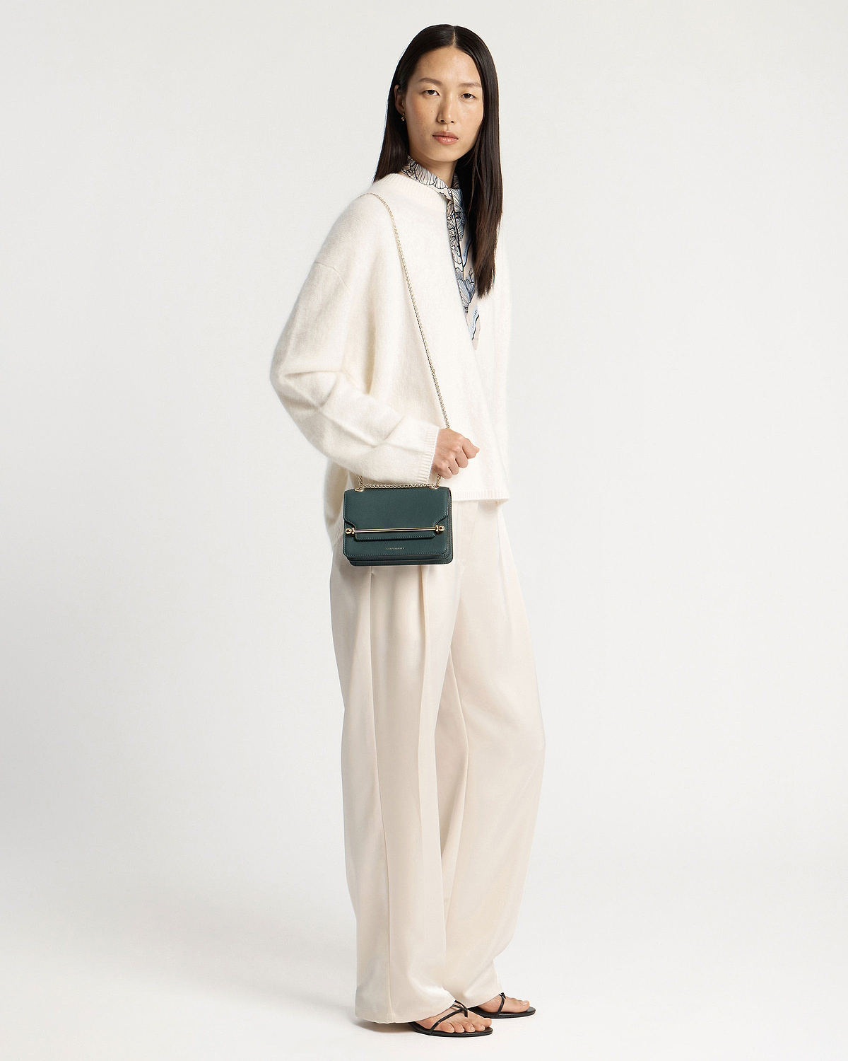 Model wearing cream outfit with bottle green East/West Mini crossbody bag
