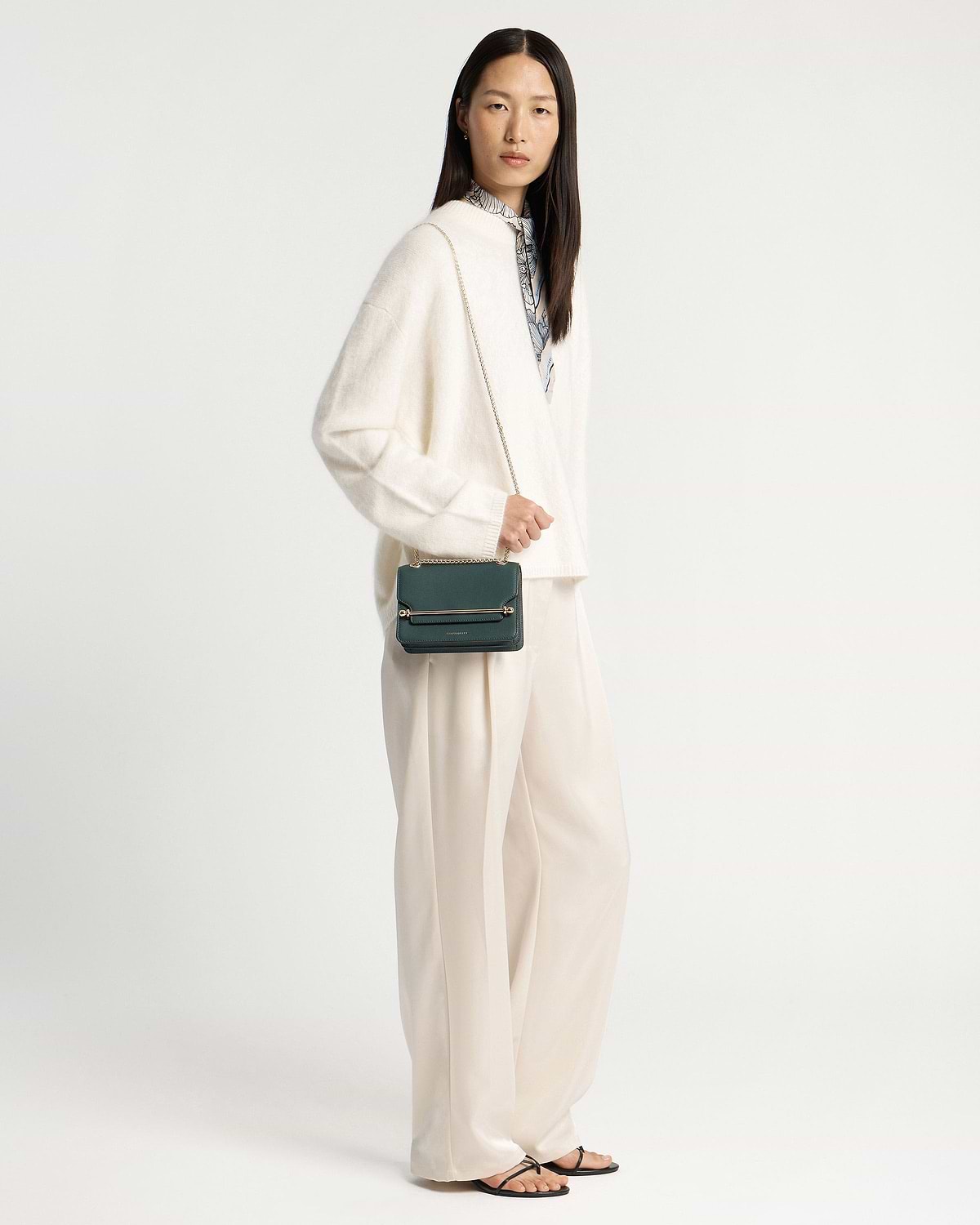 Model wearing cream outfit with bottle green East/West Mini crossbody bag