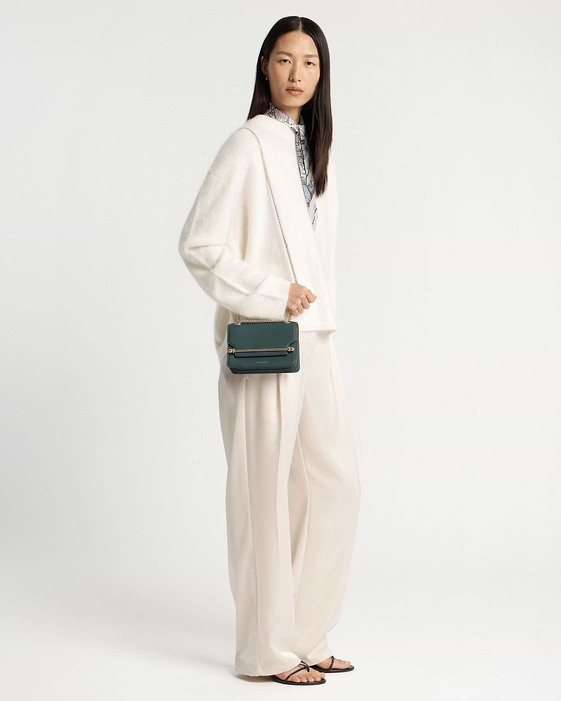 Model wearing cream outfit with bottle green East/West Mini crossbody bag