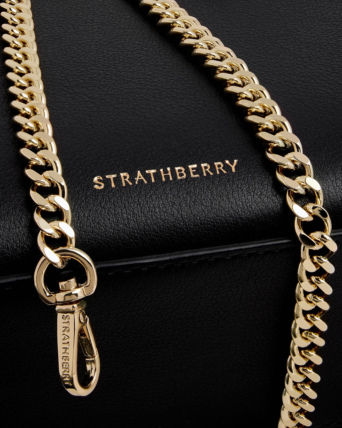 Black Strathberry nano tote close-up showing gold chain strap and logo.