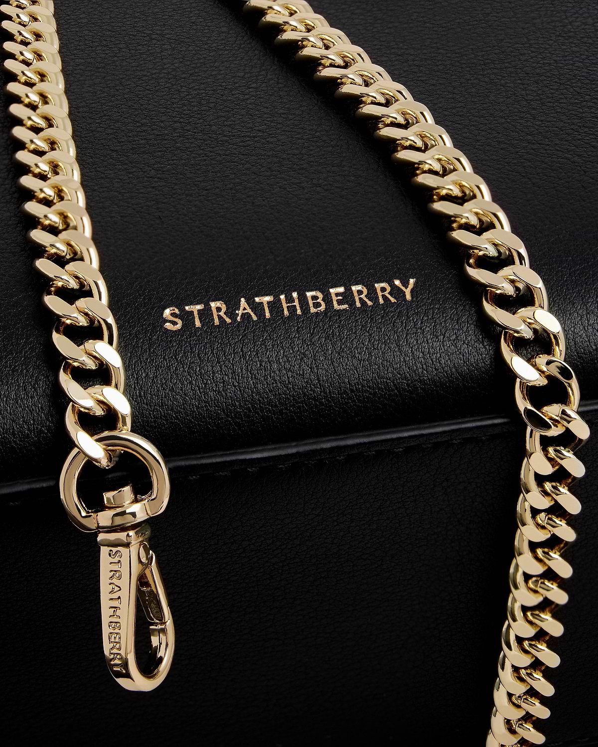 Black Strathberry nano tote close-up showing gold chain strap and logo.