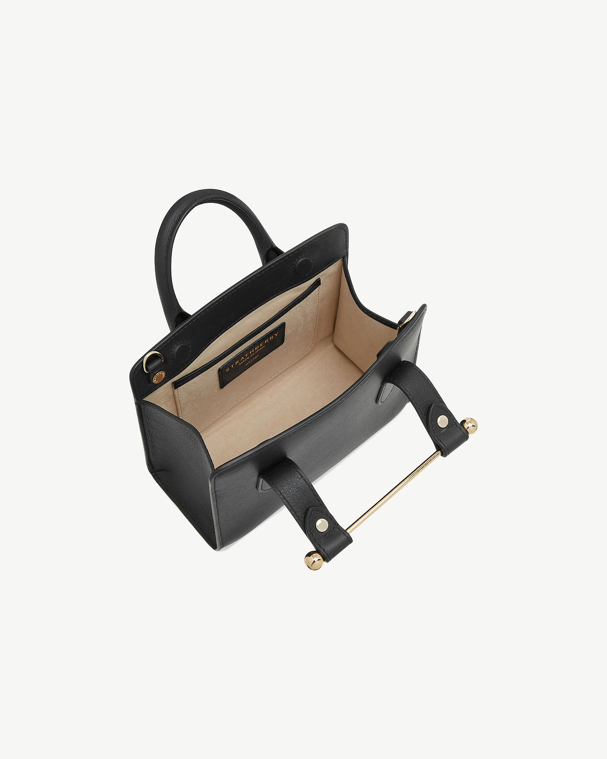 Black Strathberry nano tote open, showing beige suede interior and gold bar handle.