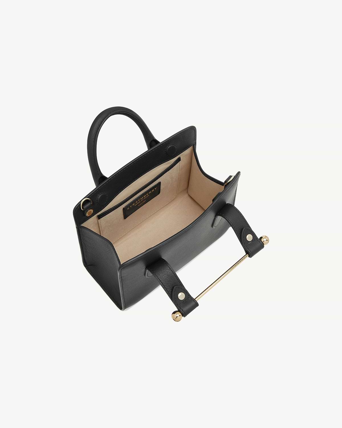 Black Strathberry nano tote open, showing beige suede interior and gold bar handle.