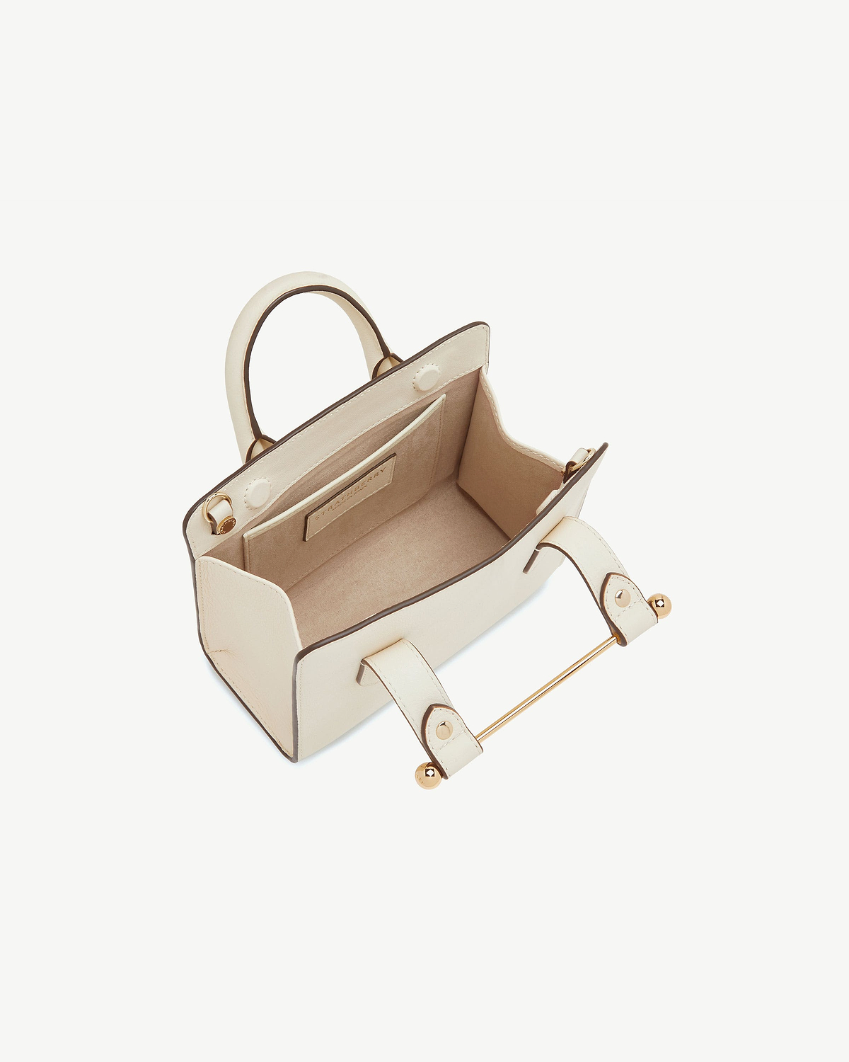 Vanilla leather nano tote with top handles and gold bar detail, open interior.