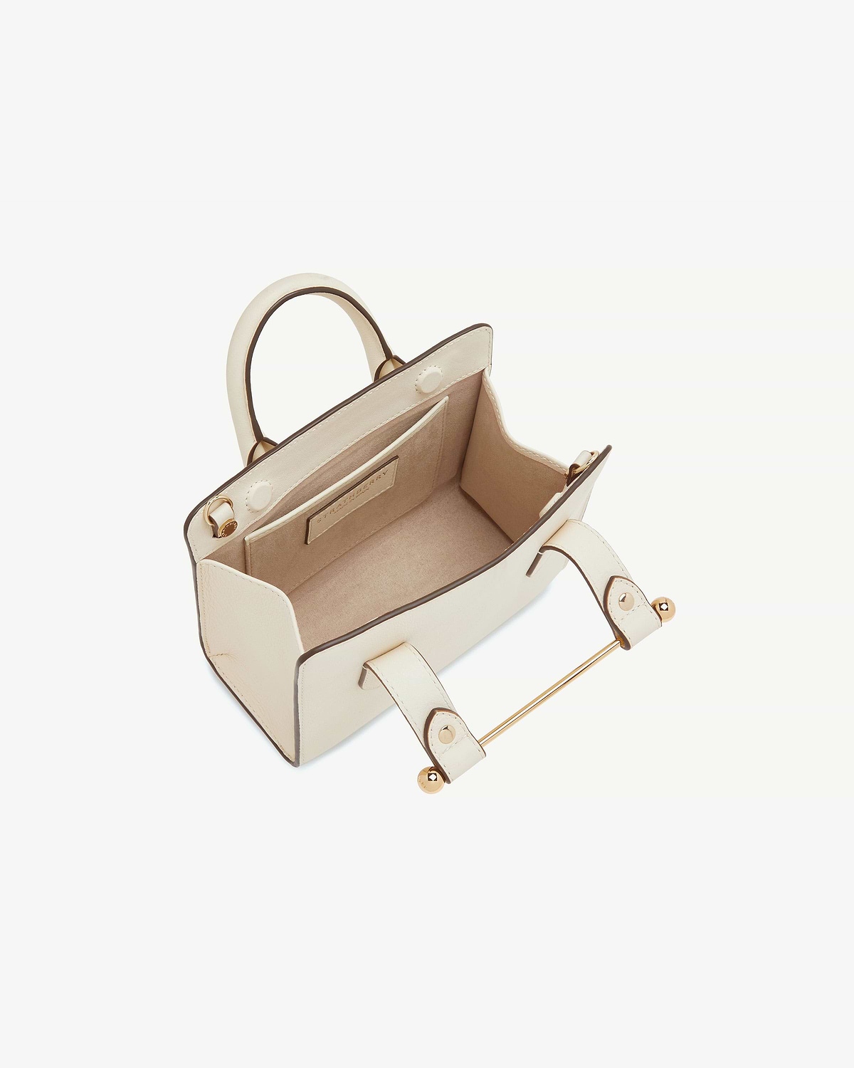 Vanilla leather nano tote with top handles and gold bar detail, open interior.