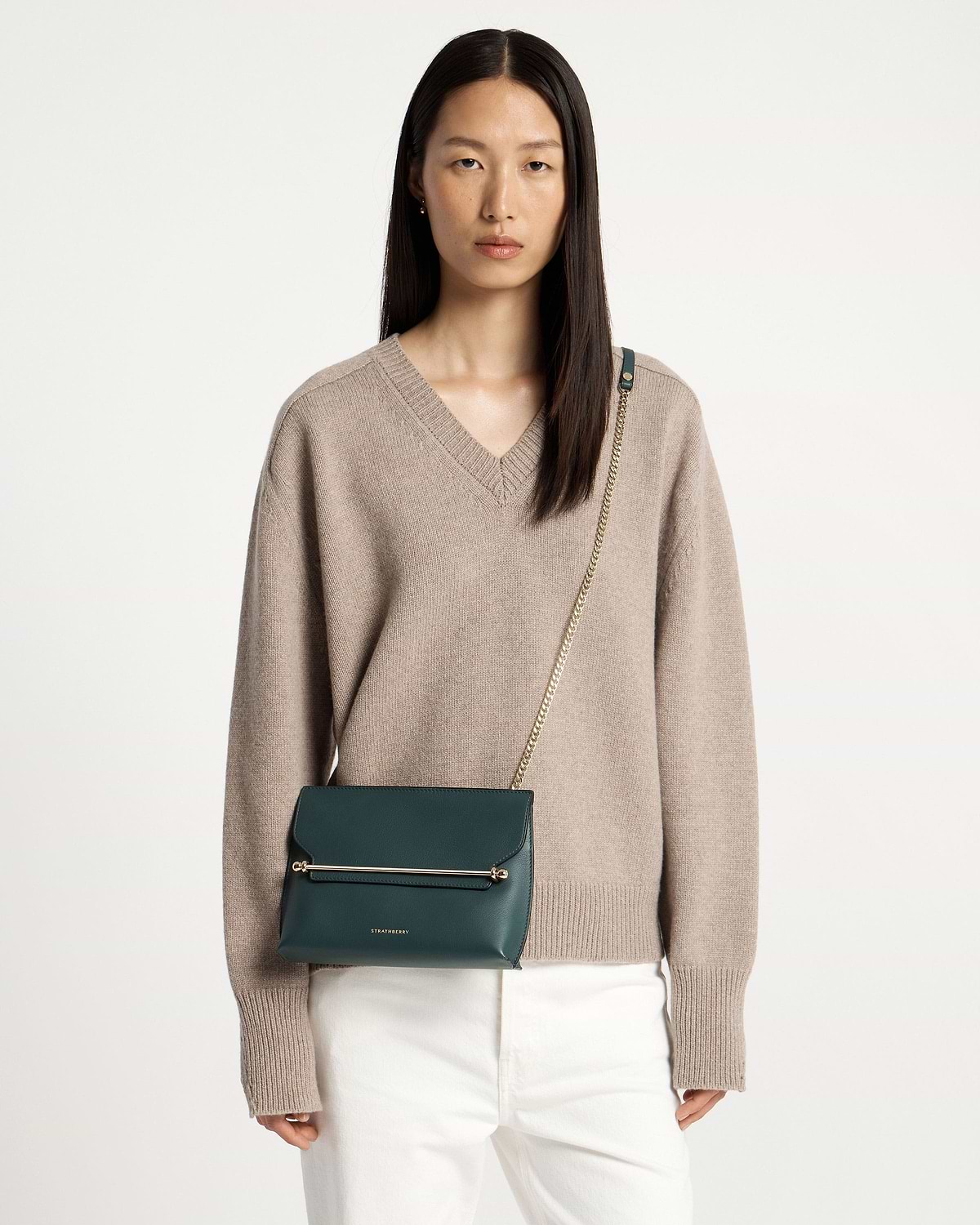 Model wearing Strathberry Stylist bottle green bag with gold chain strap