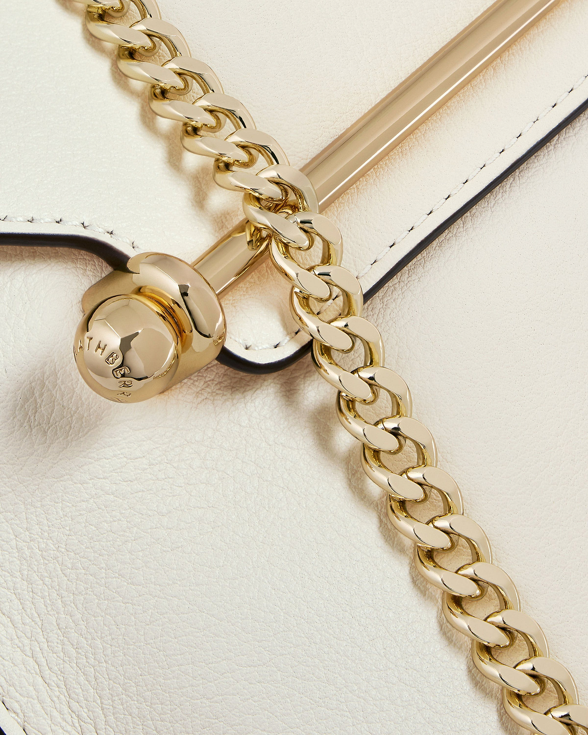 Vanilla leather bag with gold chain and polished bar hardware, stitched edge visible.