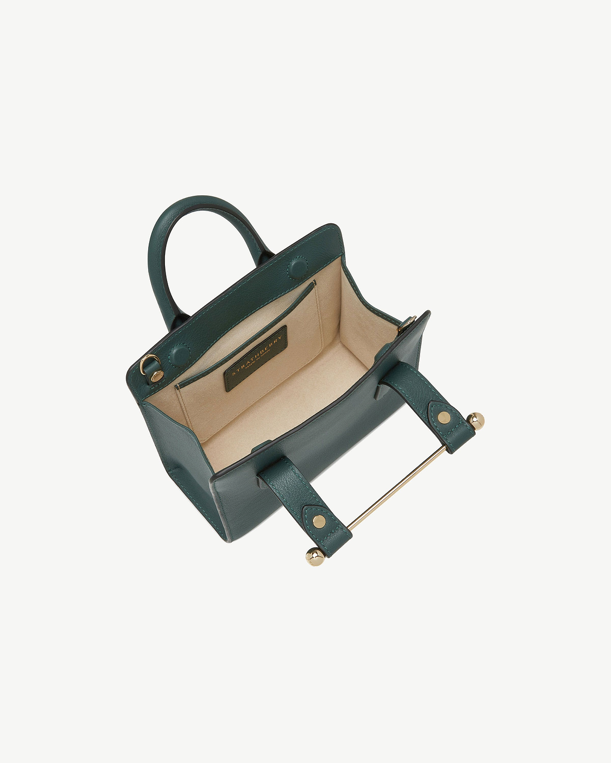 Bottle green Strathberry Nano tote open, showing beige interior and gold bar closure.