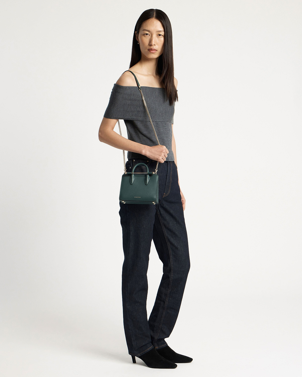 Model wearing off-shoulder top holding bottle green nano tote with chain strap.