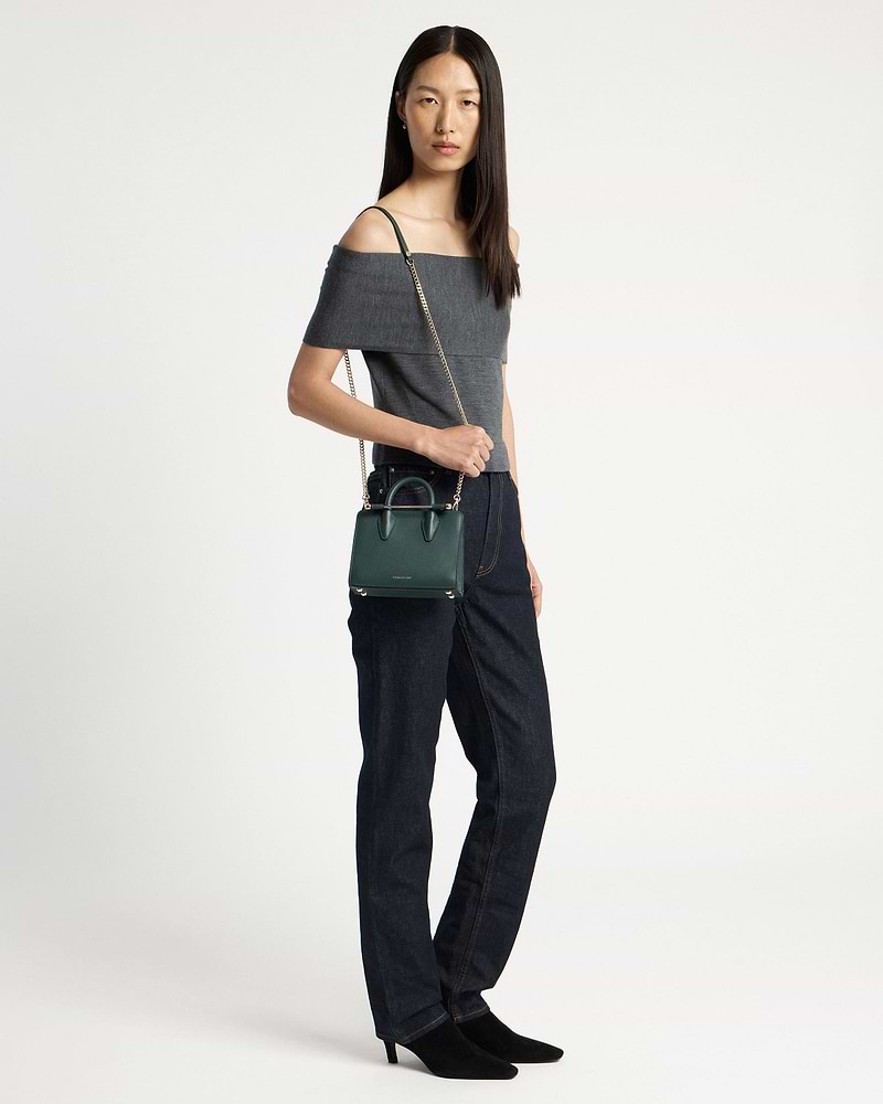 Model wearing off-shoulder top holding bottle green nano tote with chain strap.