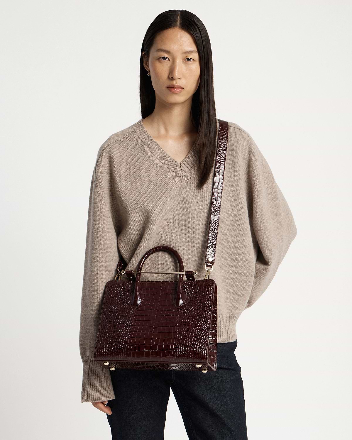 Model wearing a croc-embossed midi tote with long shoulder strap.