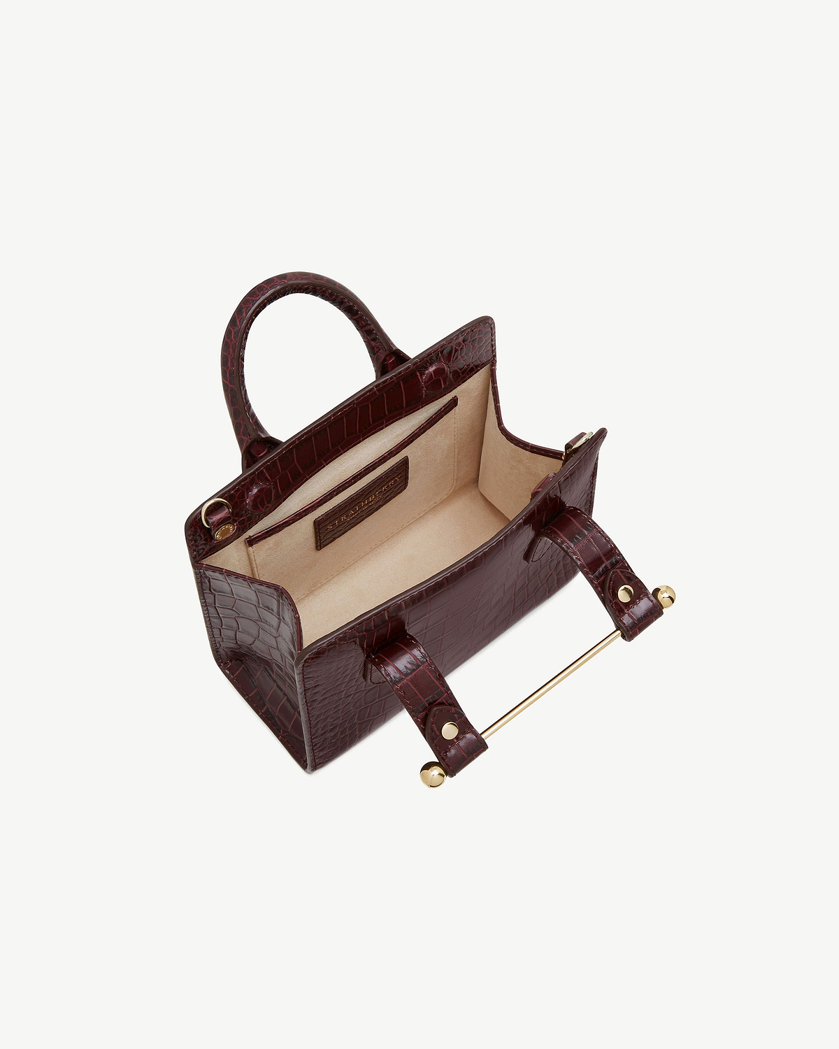 Croc-embossed nano tote with top handles and beige lining, open interior.