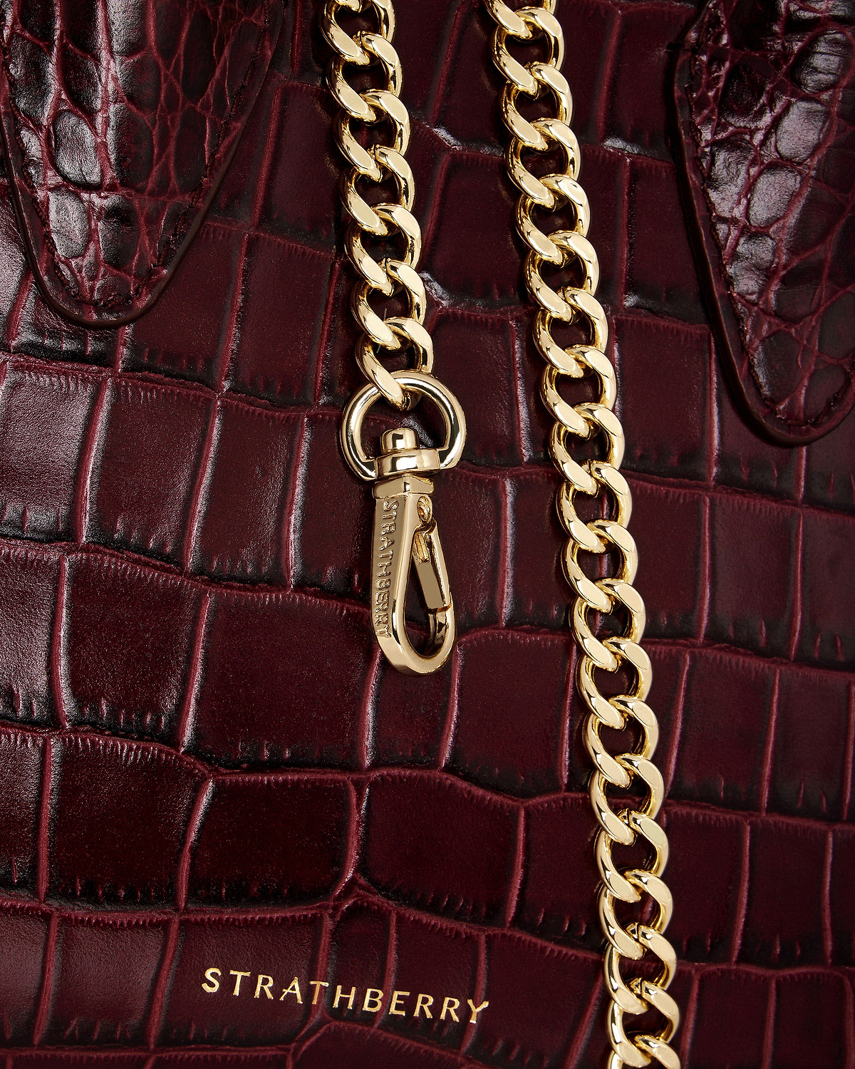 Burgundy croc-embossed leather nano tote with gold chain and Strathberry logo.