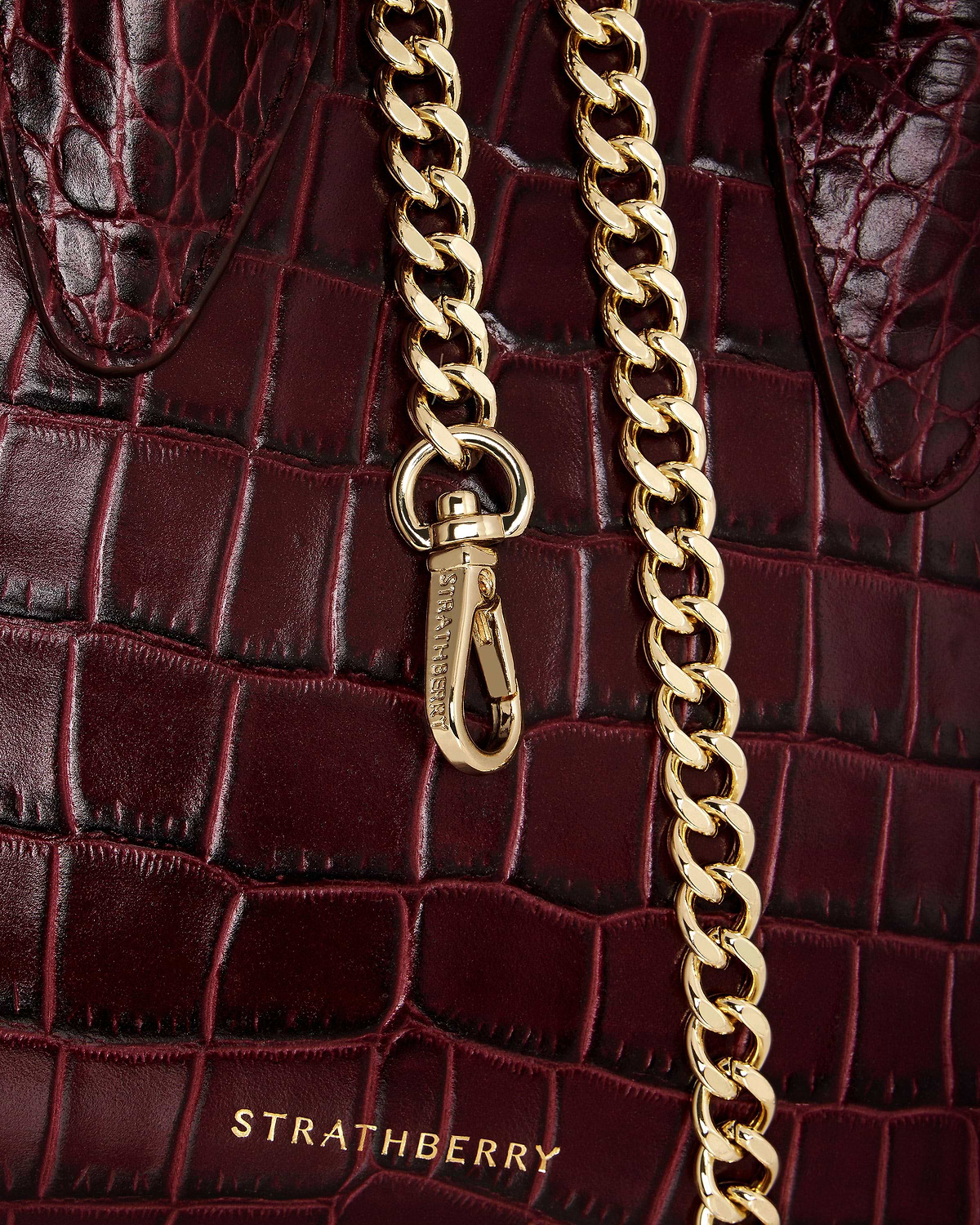 Burgundy croc-embossed leather nano tote with gold chain and Strathberry logo.