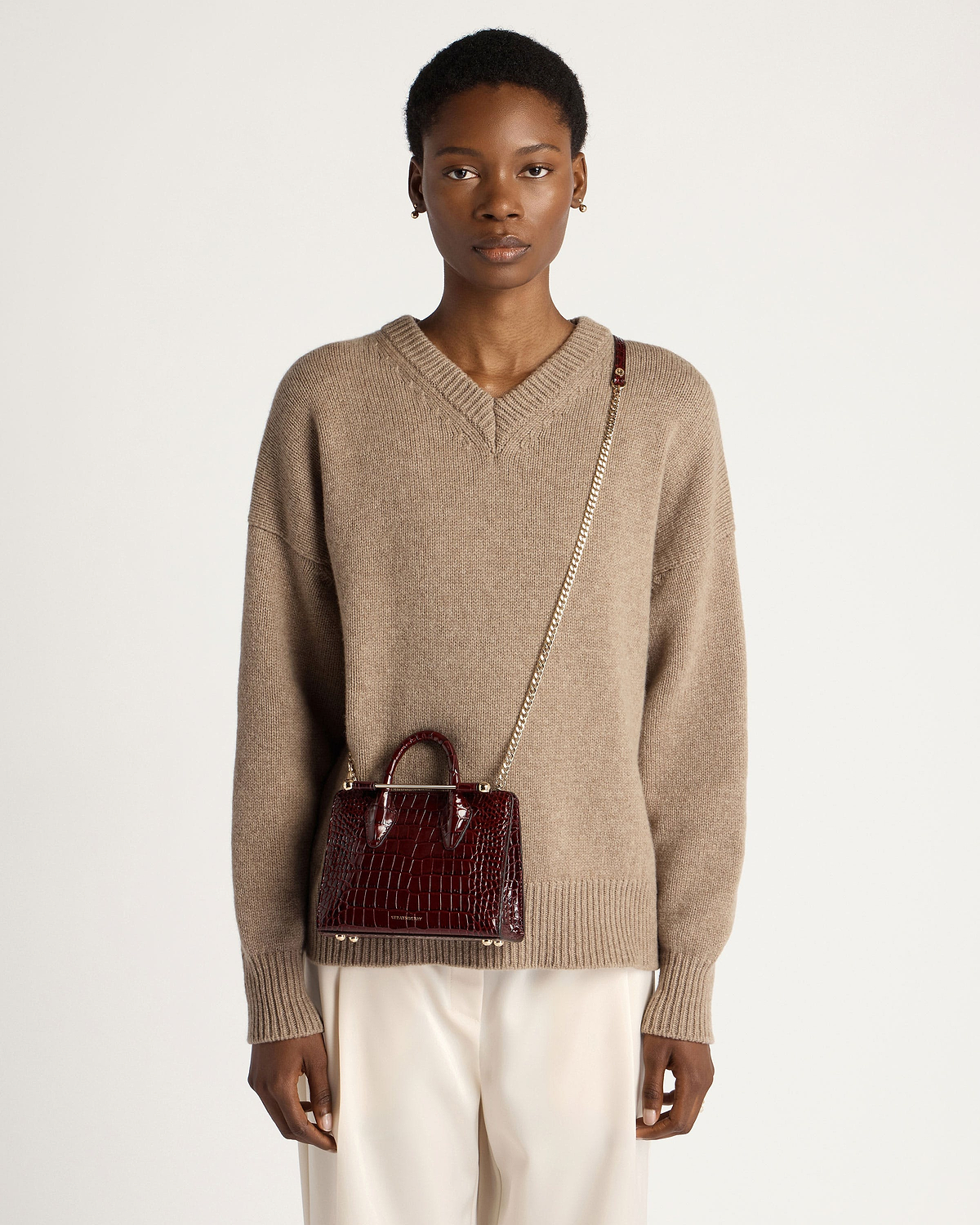 Model wearing dark red croc nano tote with gold chain crossbody strap.