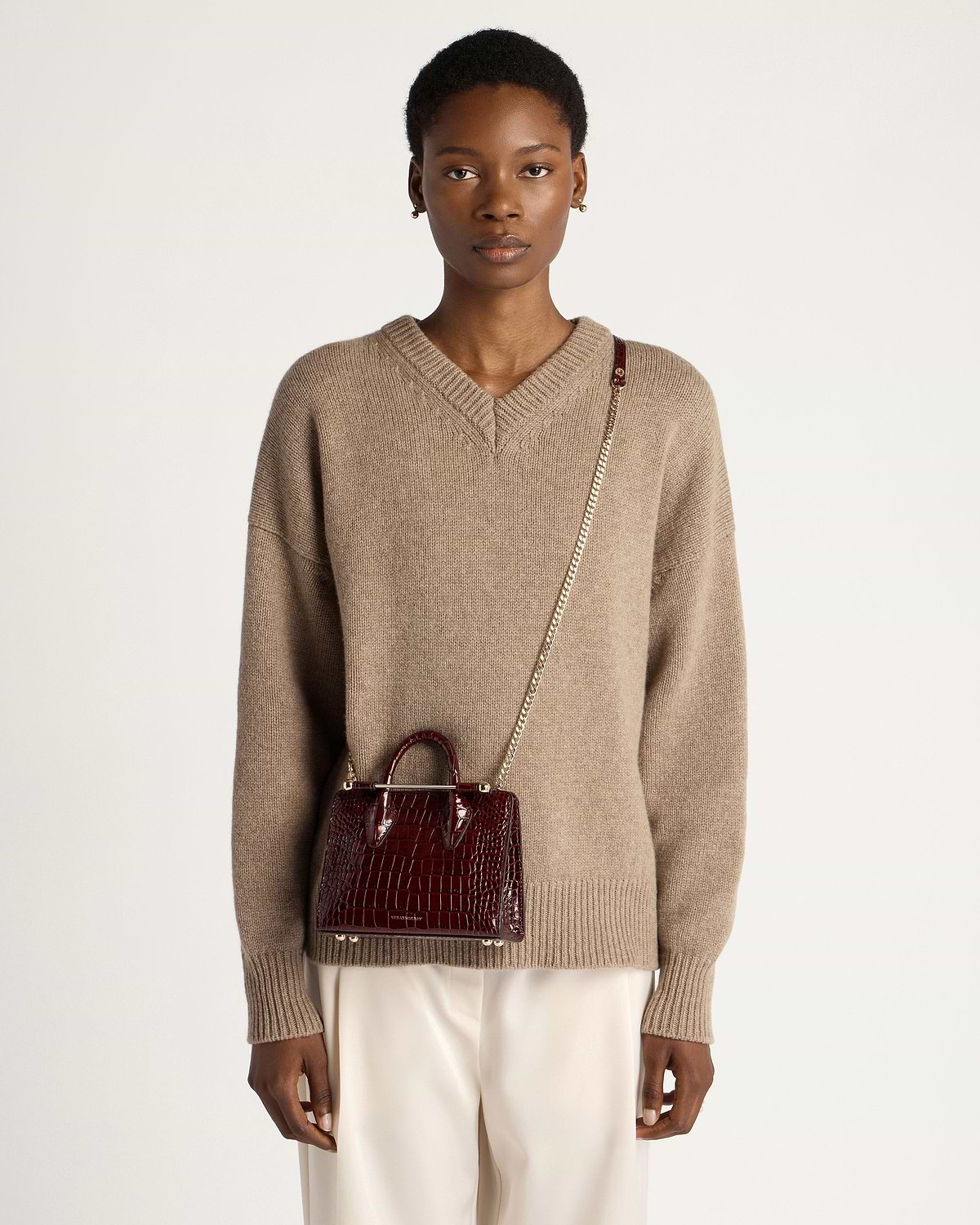 Model wearing dark red croc nano tote with gold chain crossbody strap.