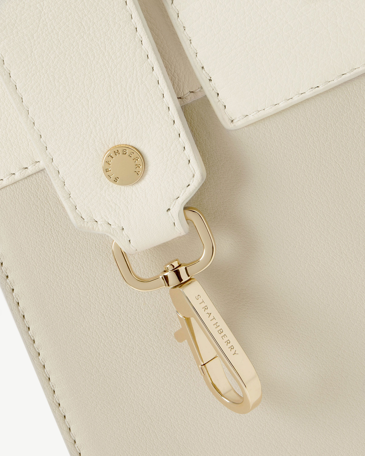 Vanilla leather strap with gold clasp engraved 'Strathberry' on cream leather.