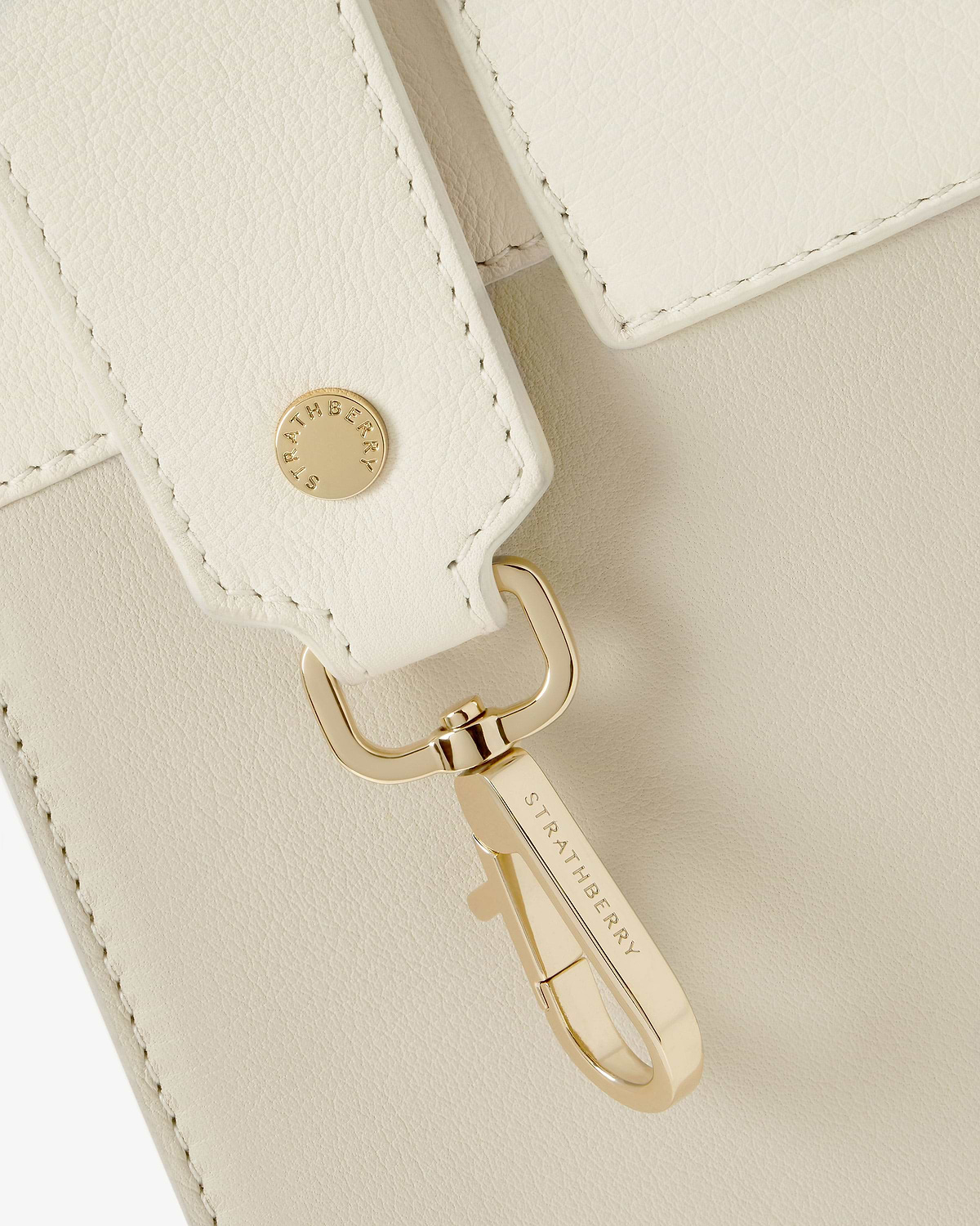 Vanilla leather strap with gold clasp engraved 'Strathberry' on cream leather.