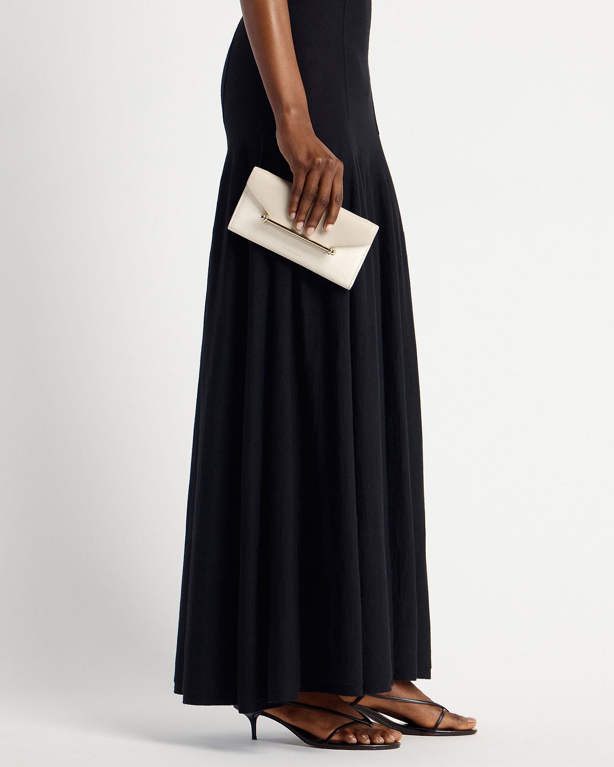 Model holding a vanilla envelope wallet with gold bar detail by her side.