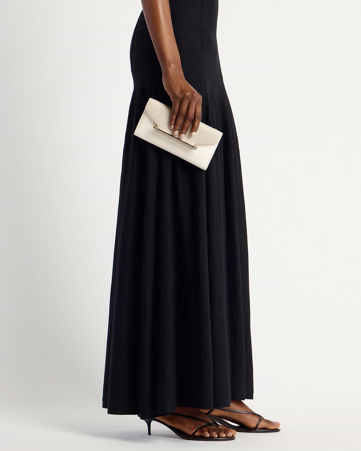 Model holding a vanilla envelope wallet with gold bar detail by her side.