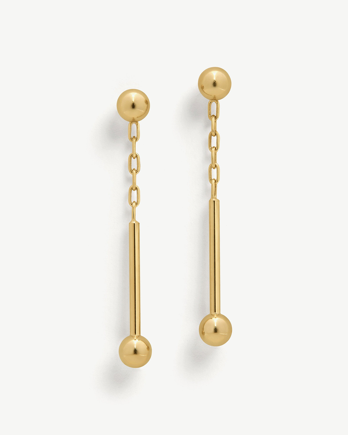 Pair of 22 carat gold gilded music bar drop earrings on a white background.