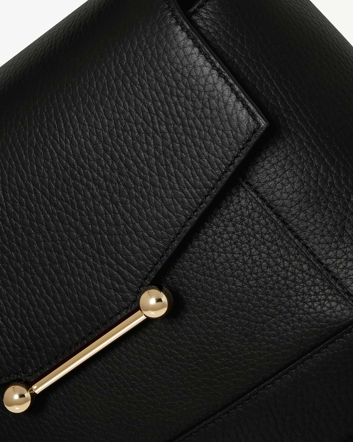 Close up of black pebbled leather mosaic bag flap with gold bar hardware.