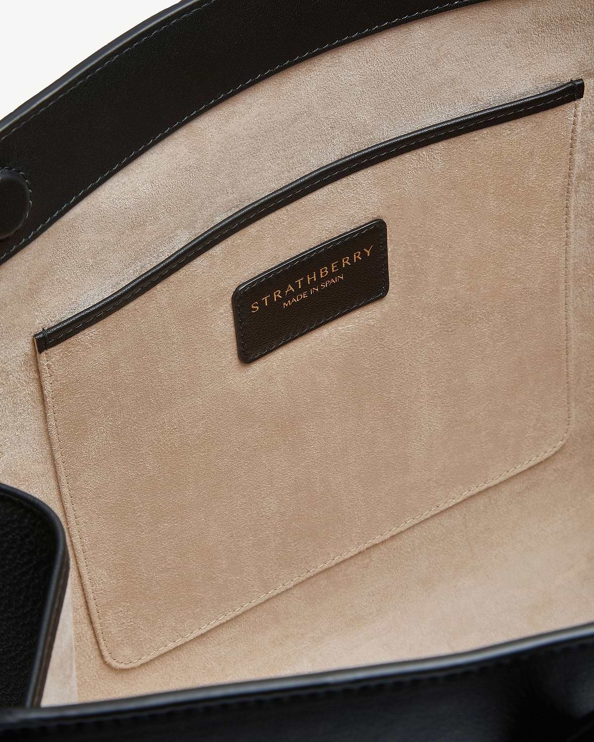 Tote interior showing beige suede pocket and black Strathberry label reading 'Made in Spain'.