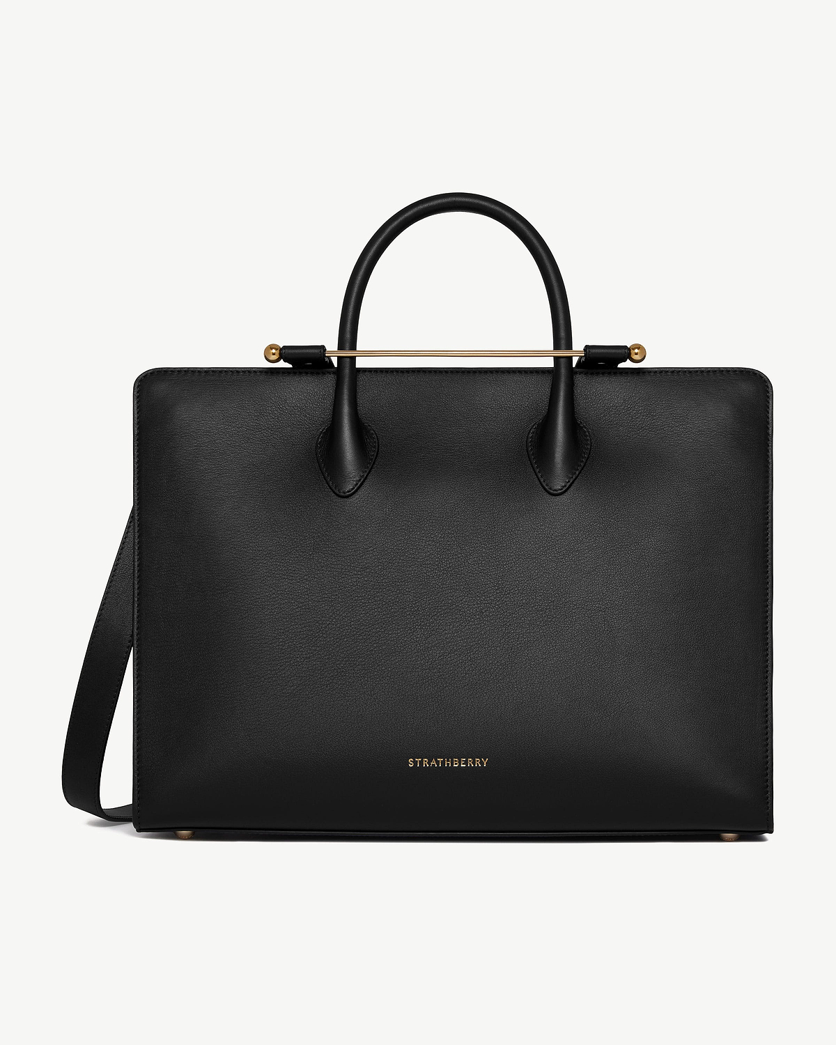 Black Strathberry leather tote with top handles, shoulder strap, and gold bar detail.