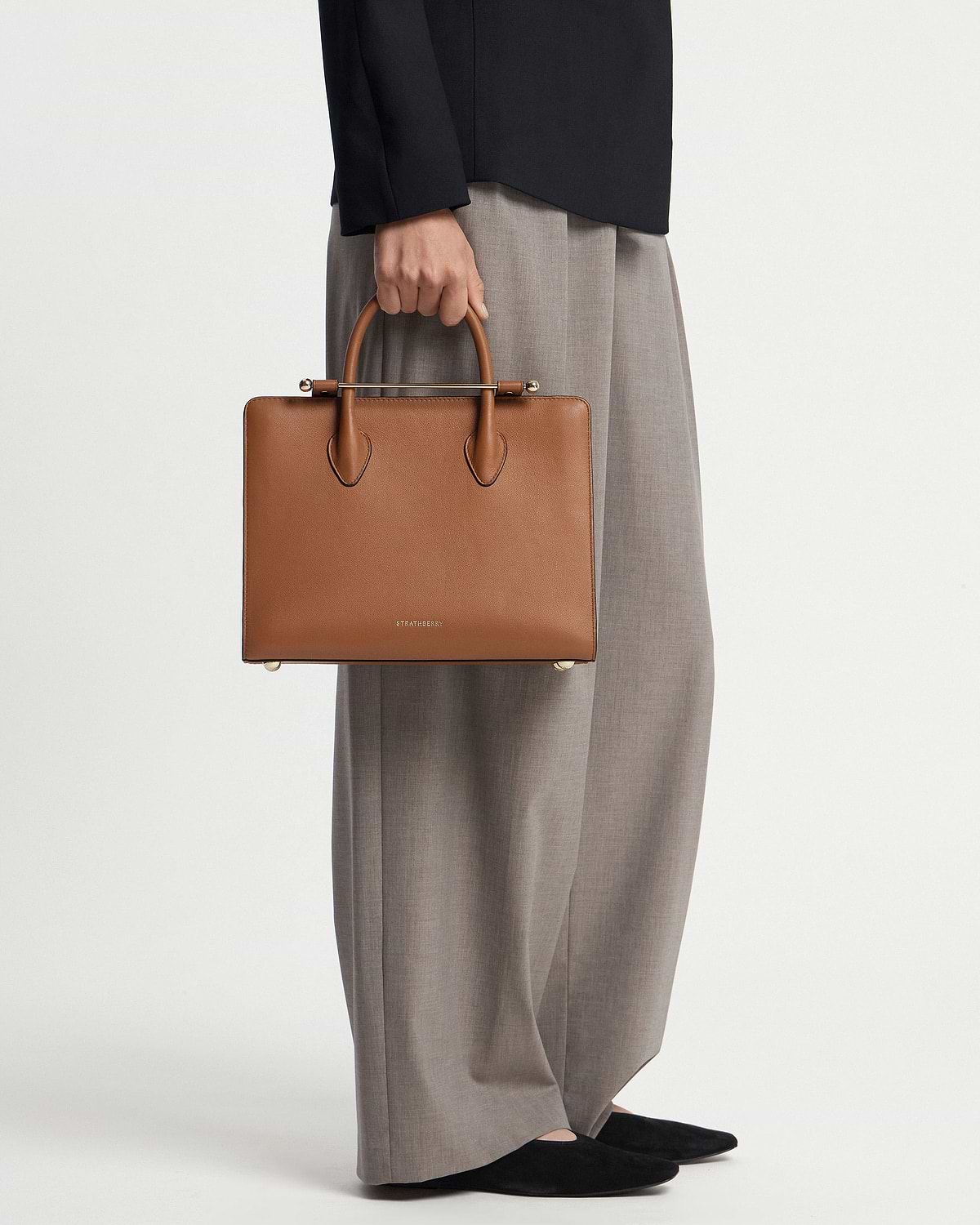 Chestnut Strathberry midi tote held by model cropped below the waist.