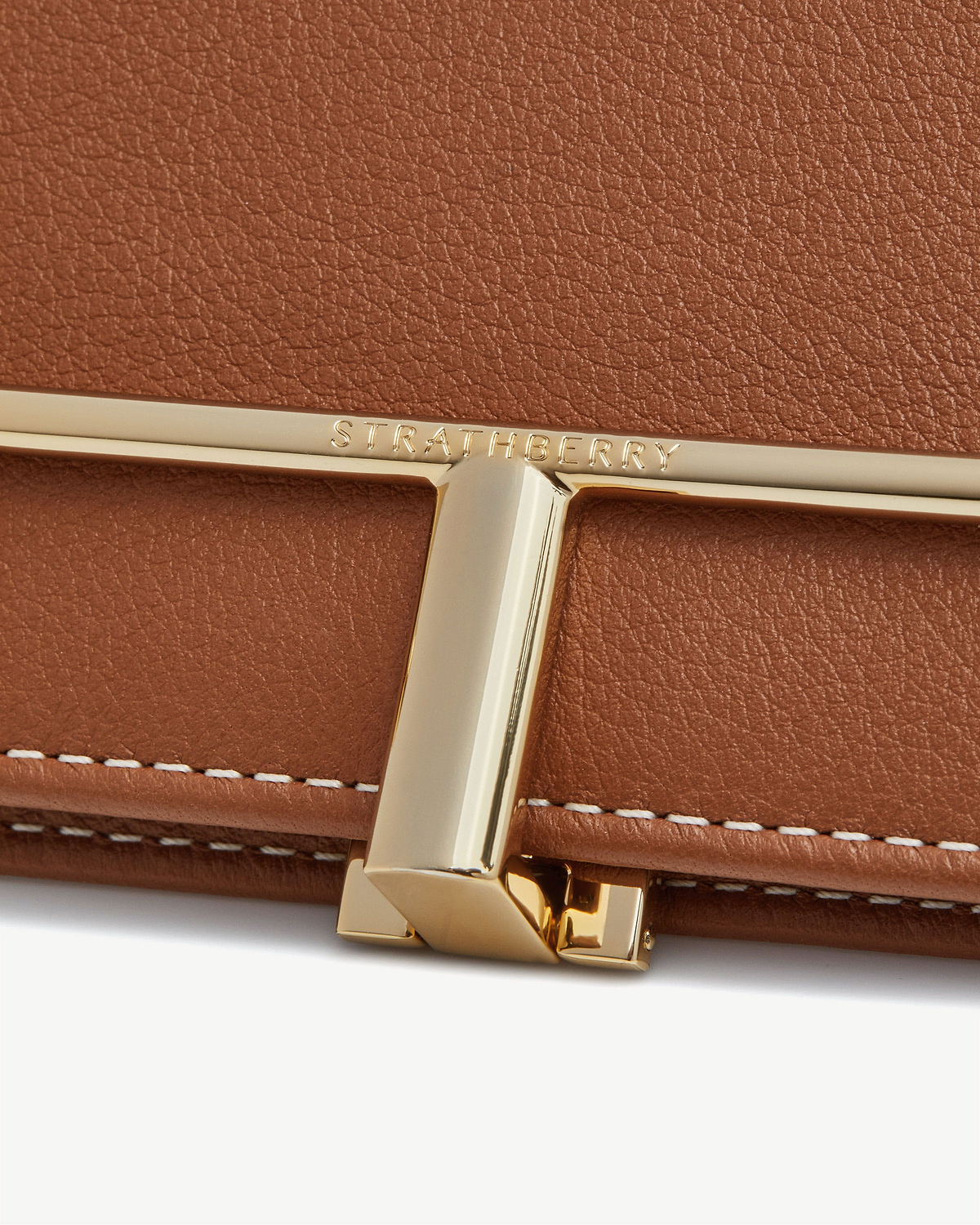 Chestnut leather wallet clasp with gold Strathberry bar and vanilla stitching.