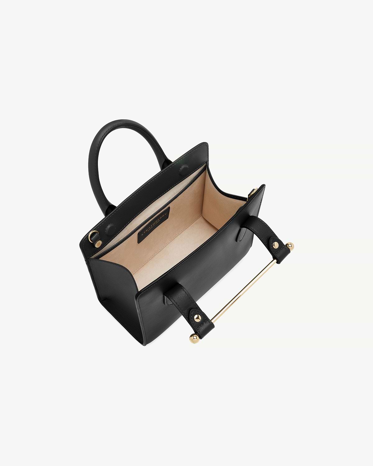 Black mini tote bag open, beige interior, top handles and gold metal bar.
