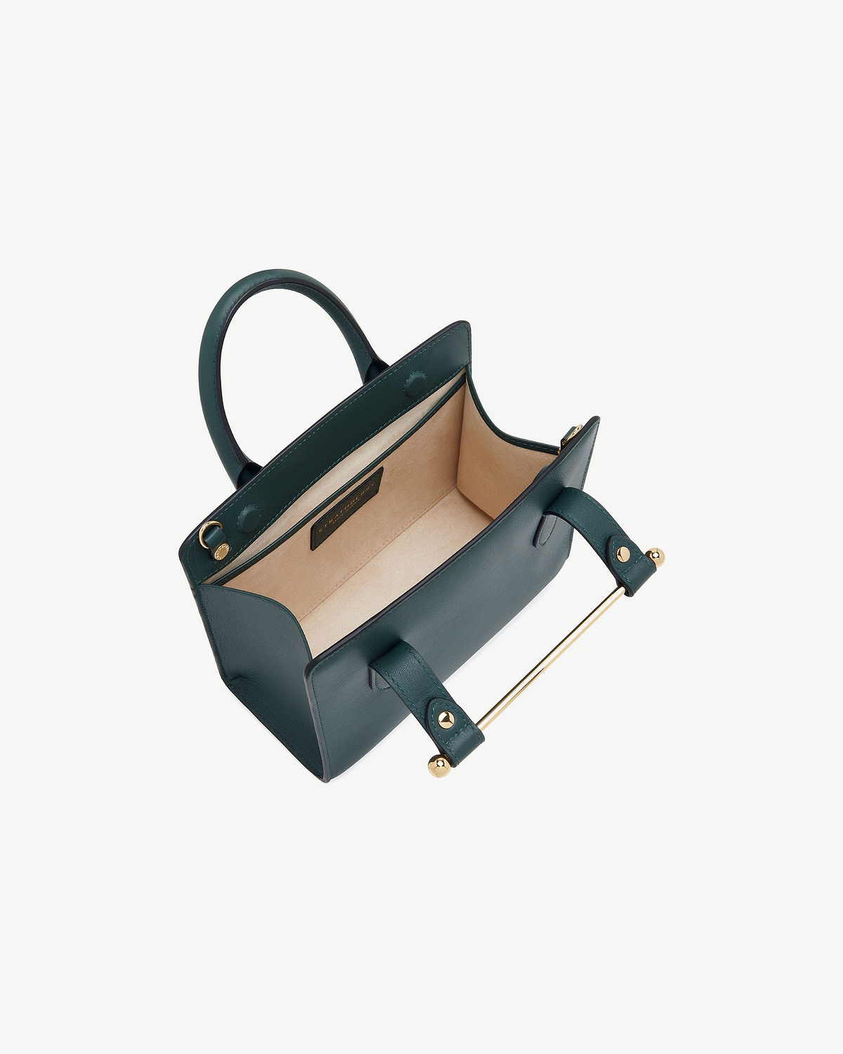 Bottle green mini tote showing beige interior and gold bar handle