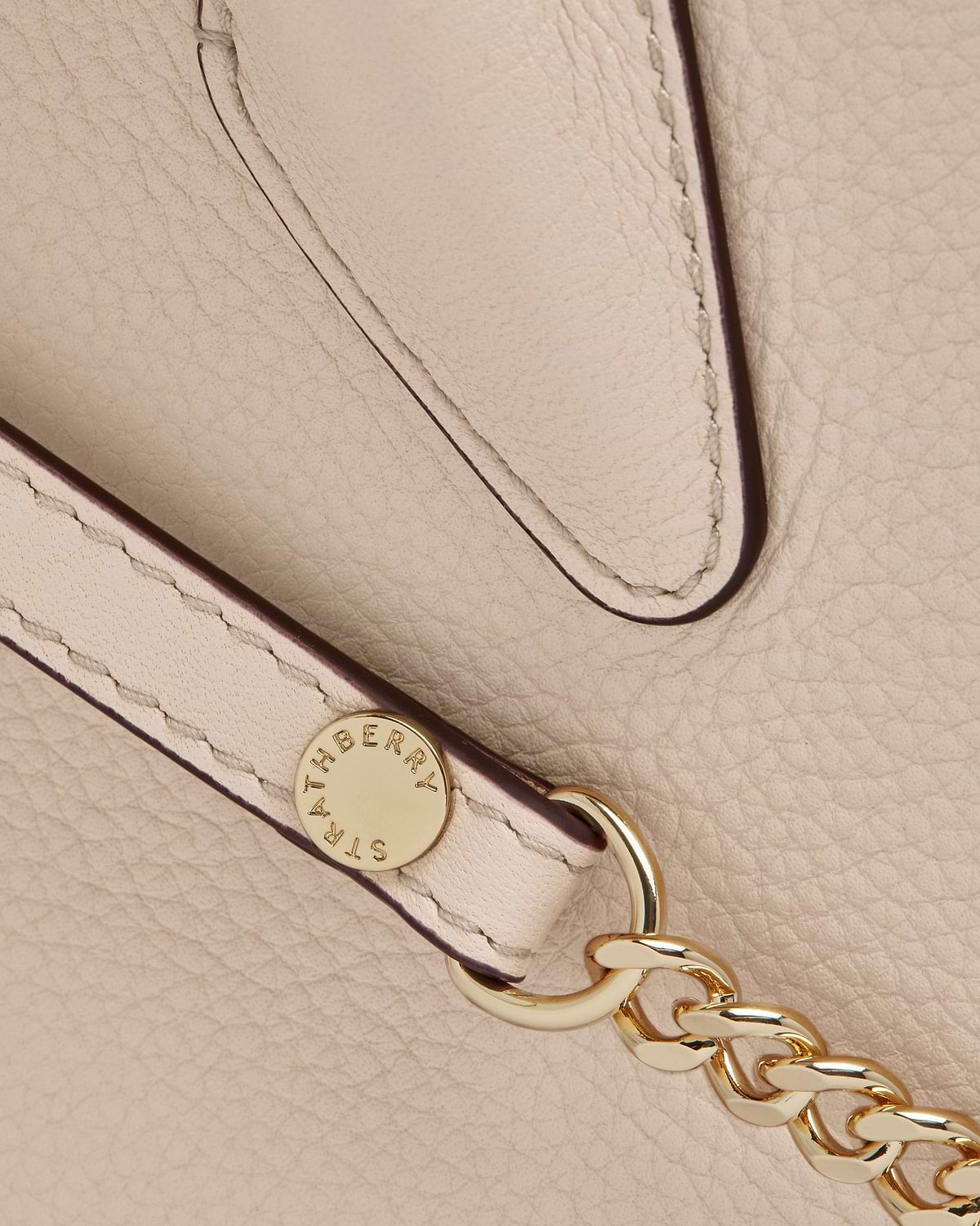 Strathberry mini tote in oat pebbled leather showing strap and gold chain hardware