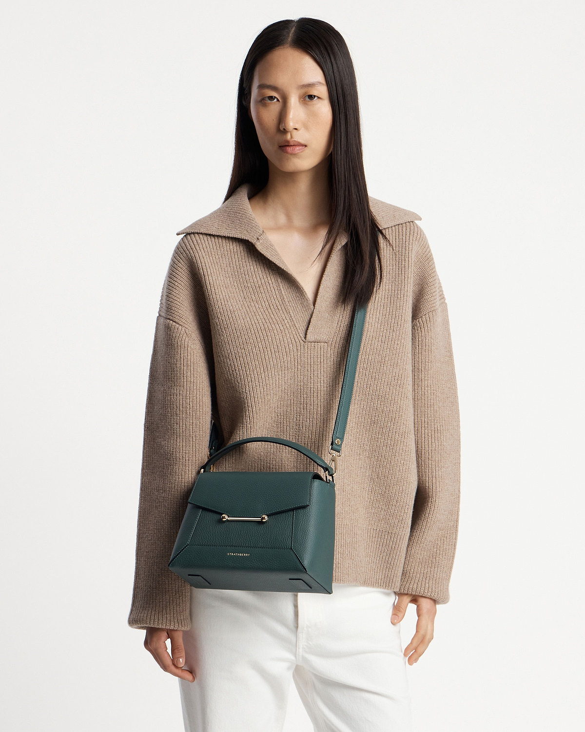 Model wearing Strathberry bottle green mosaic bag with top handle, shoulder strap, and gold bar.