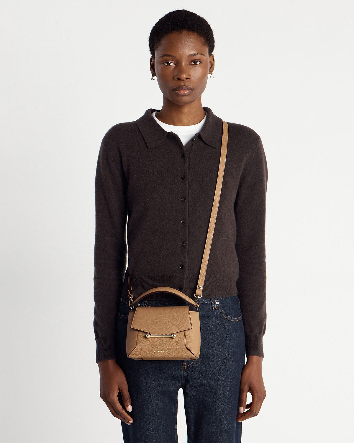 Model wearing a Strathberry Mosaic Nano caramel leather crossbody bag.