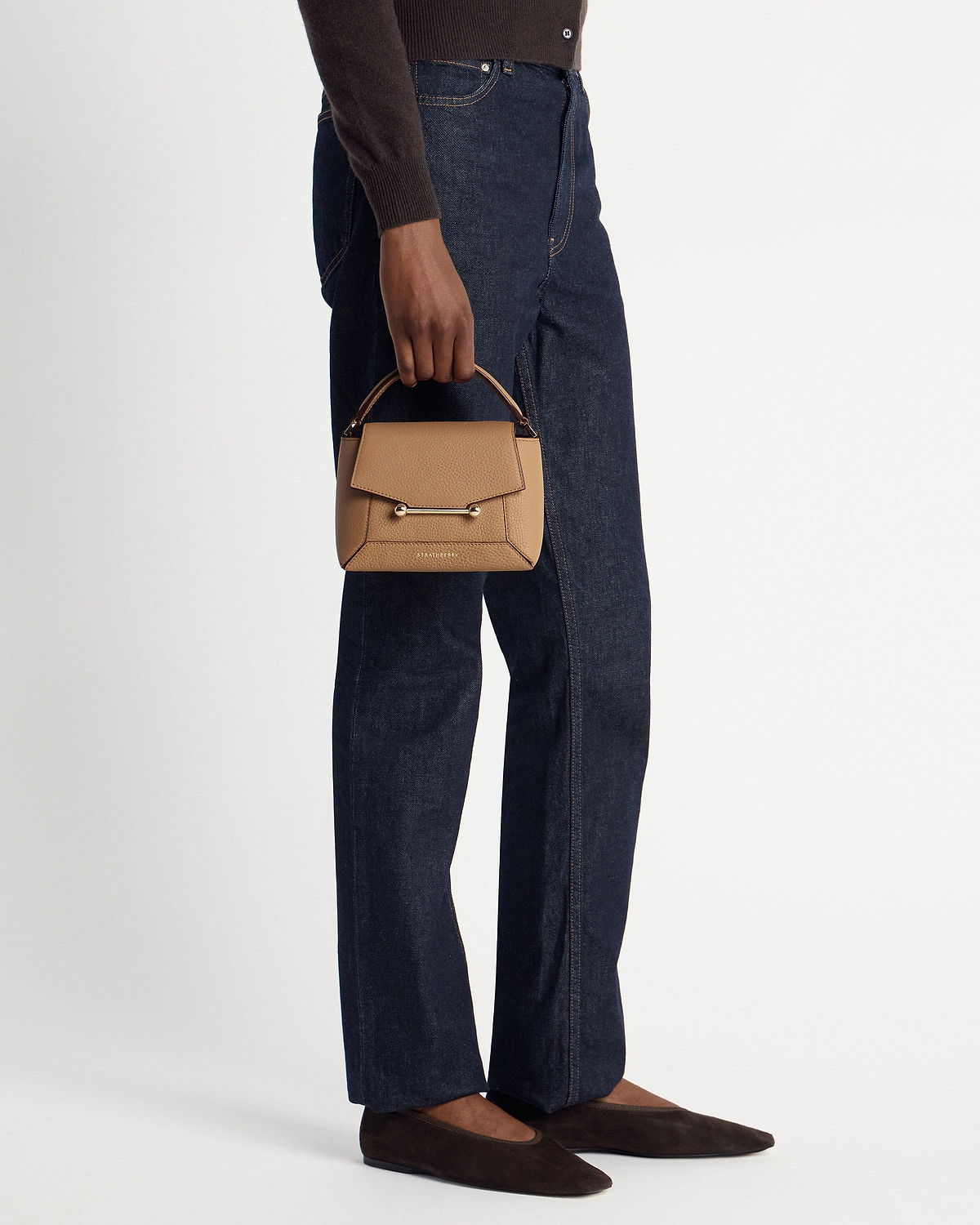 Model holding caramel Mosaic Nano bag with gold bar and visible Strathberry logo