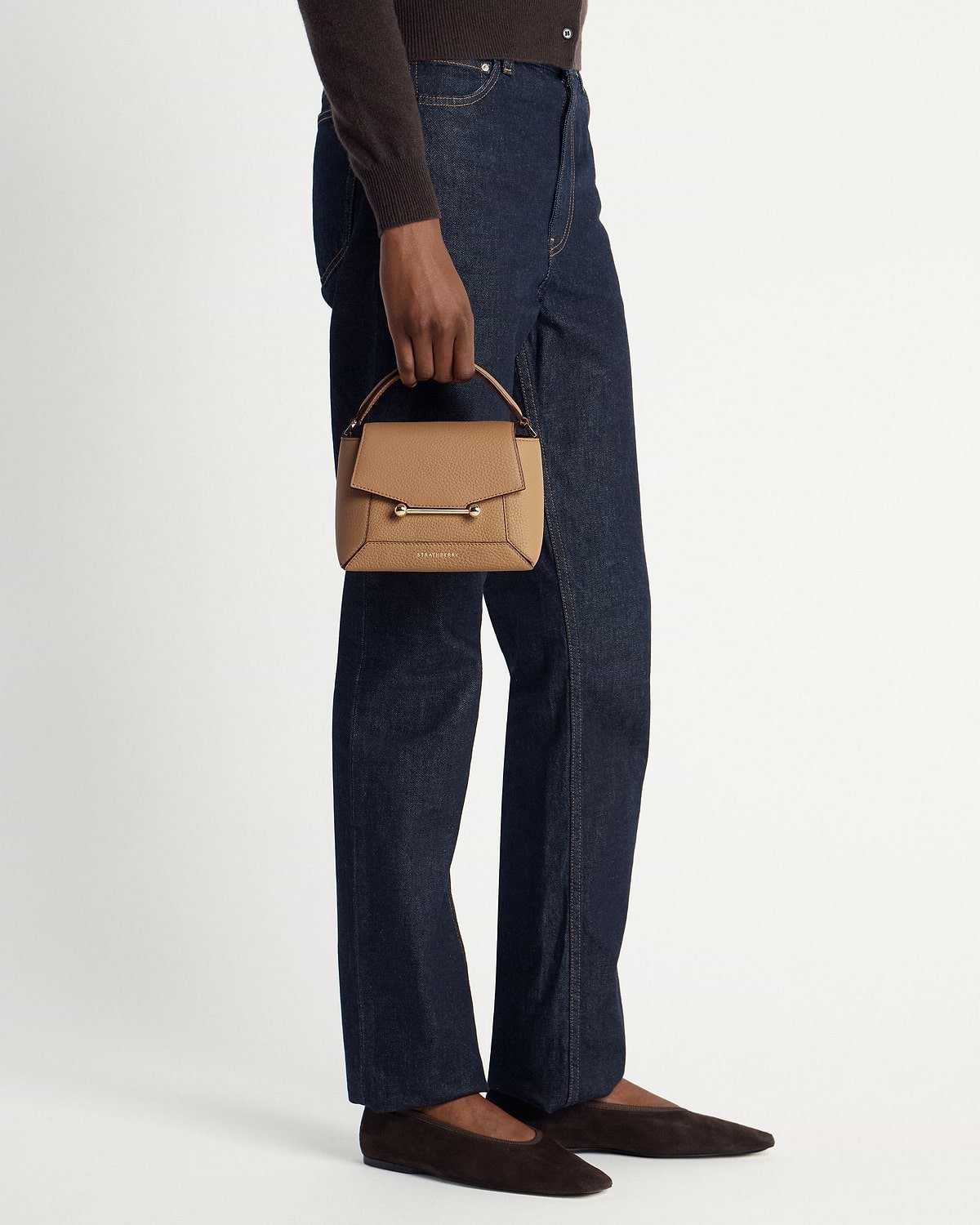 Model holding caramel Mosaic Nano bag with gold bar and visible Strathberry logo