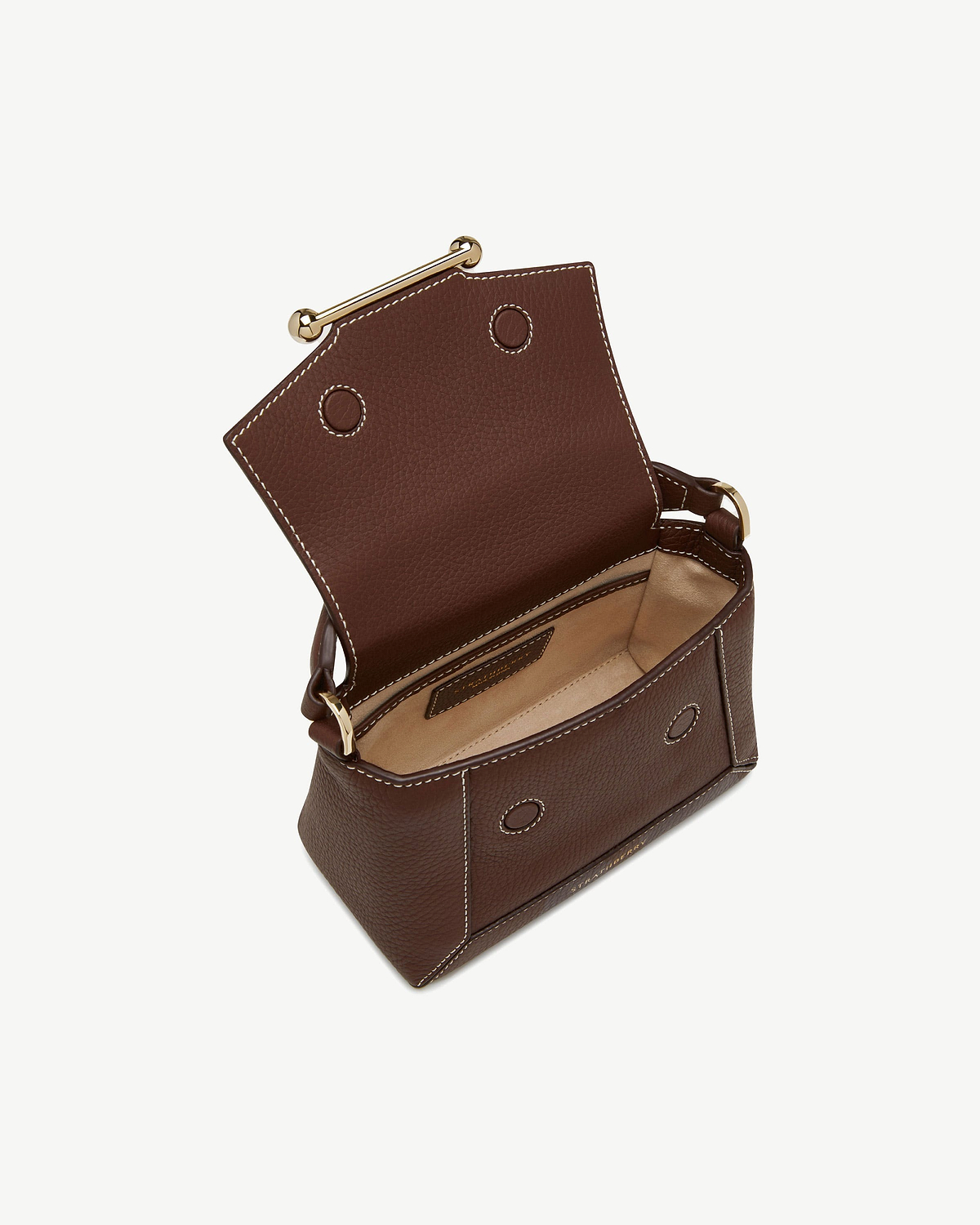 Small chocolate leather bag with vanilla stitching, gold bar closure, flap open showing beige interior.