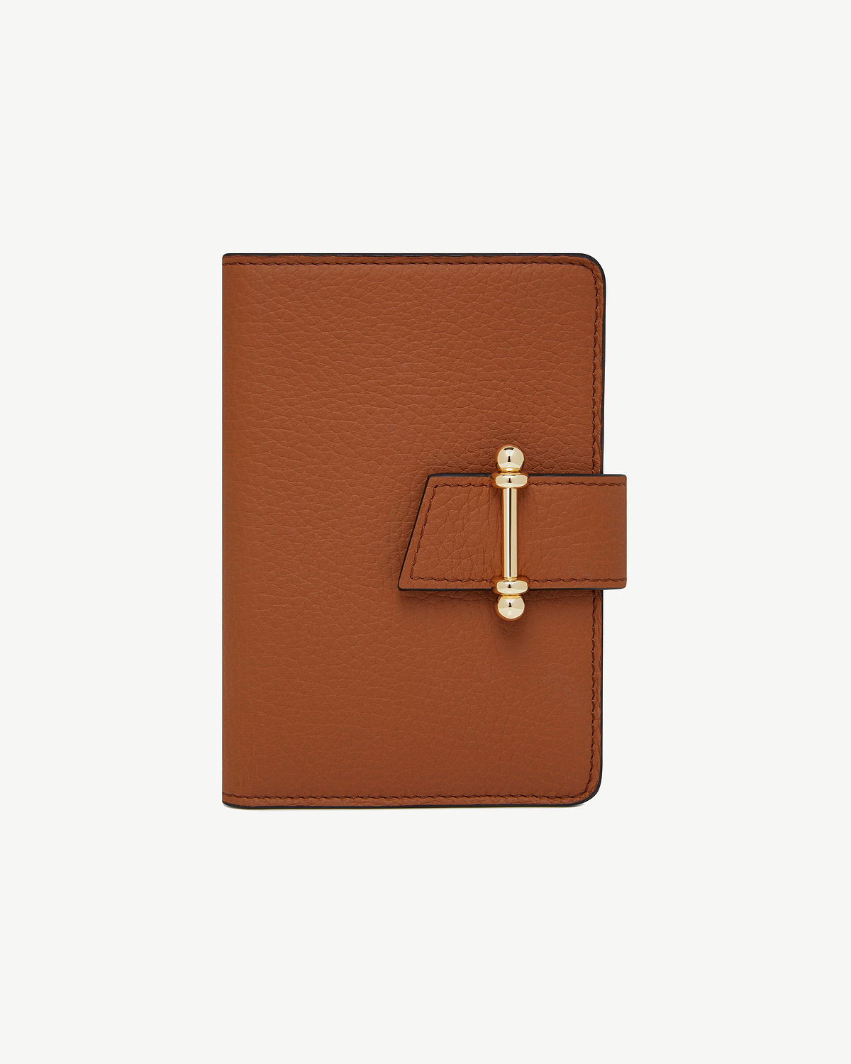 Tan leather passport holder with pebbled texture and gold bar clasp.