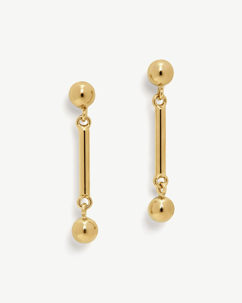 Pair of 22 carat gold gilded music bar drop earrings on white background