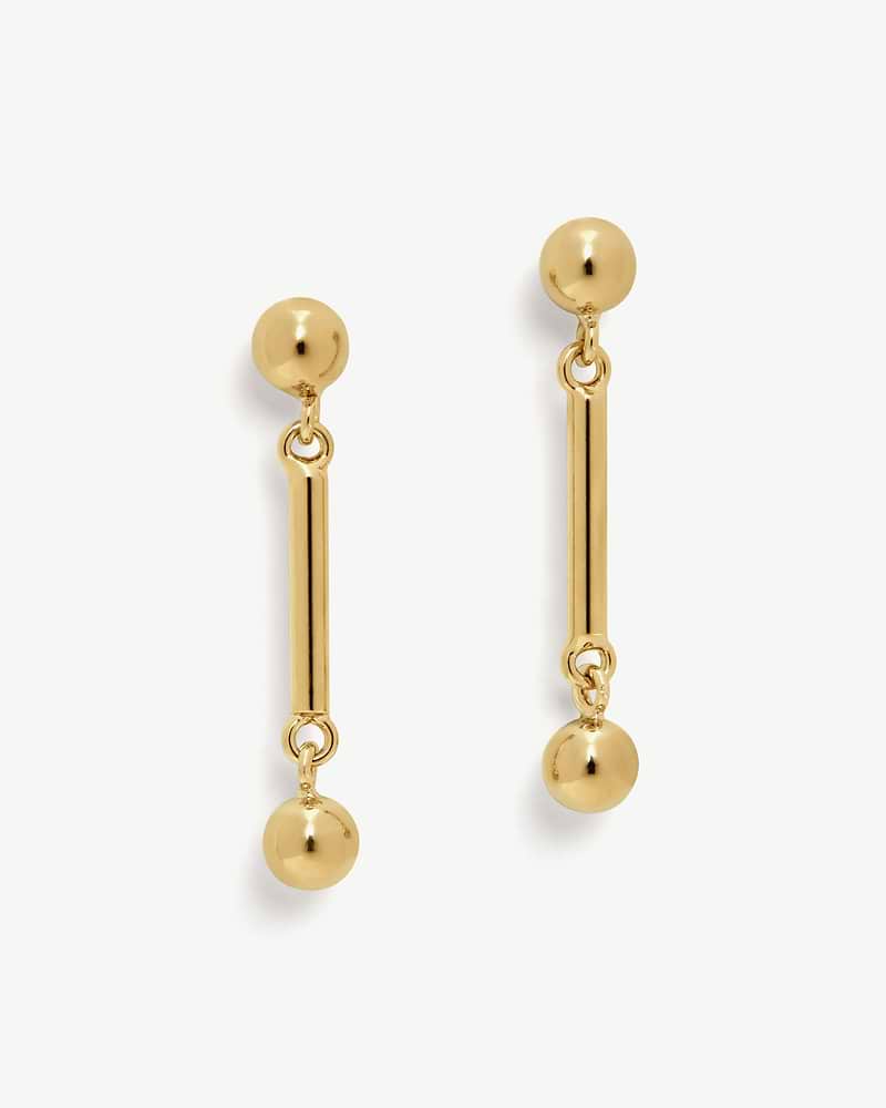 Pair of 22 carat gold gilded music bar drop earrings on white background