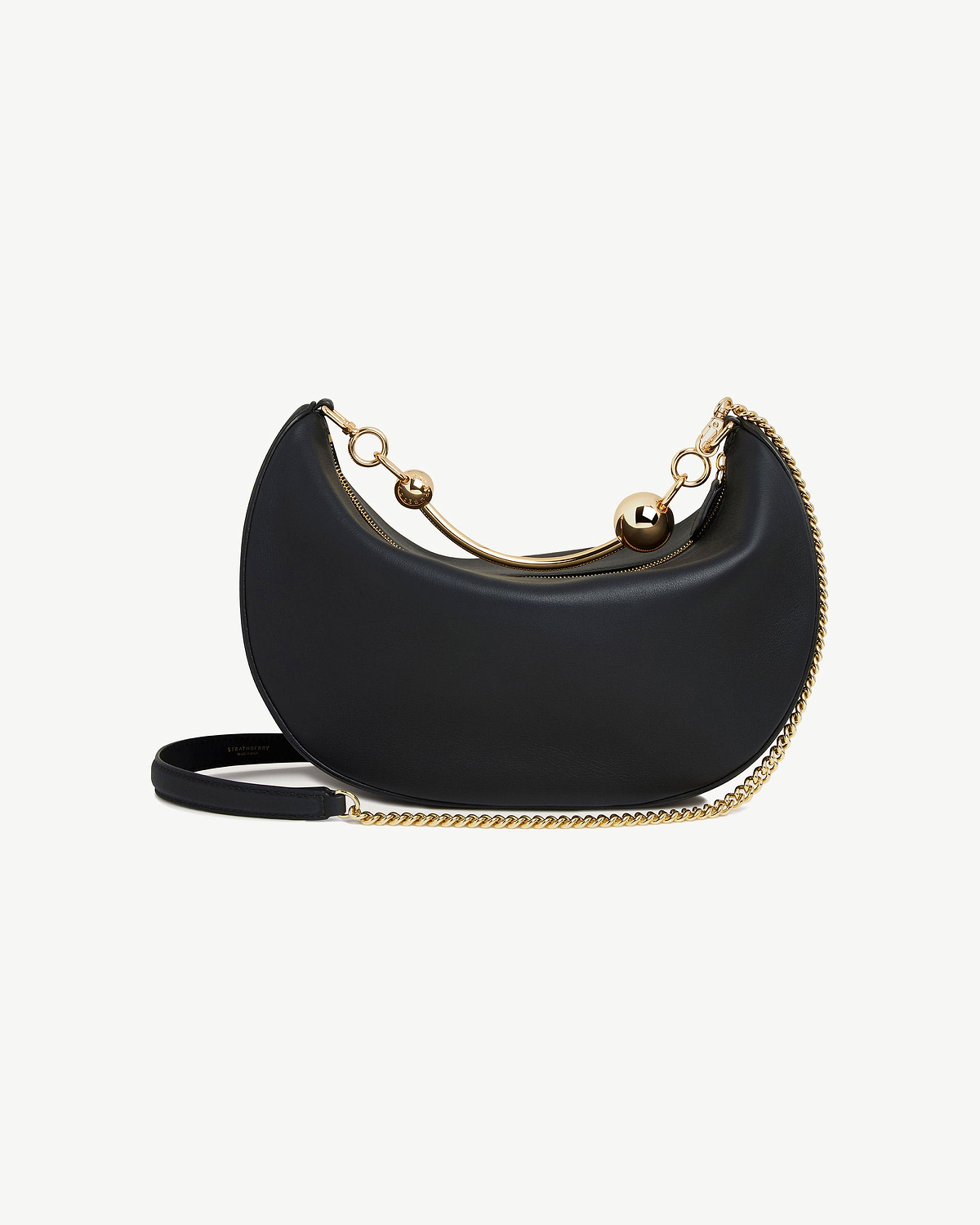 Black crescent-shaped leather bag with gold chain strap and curved handle with ball details.