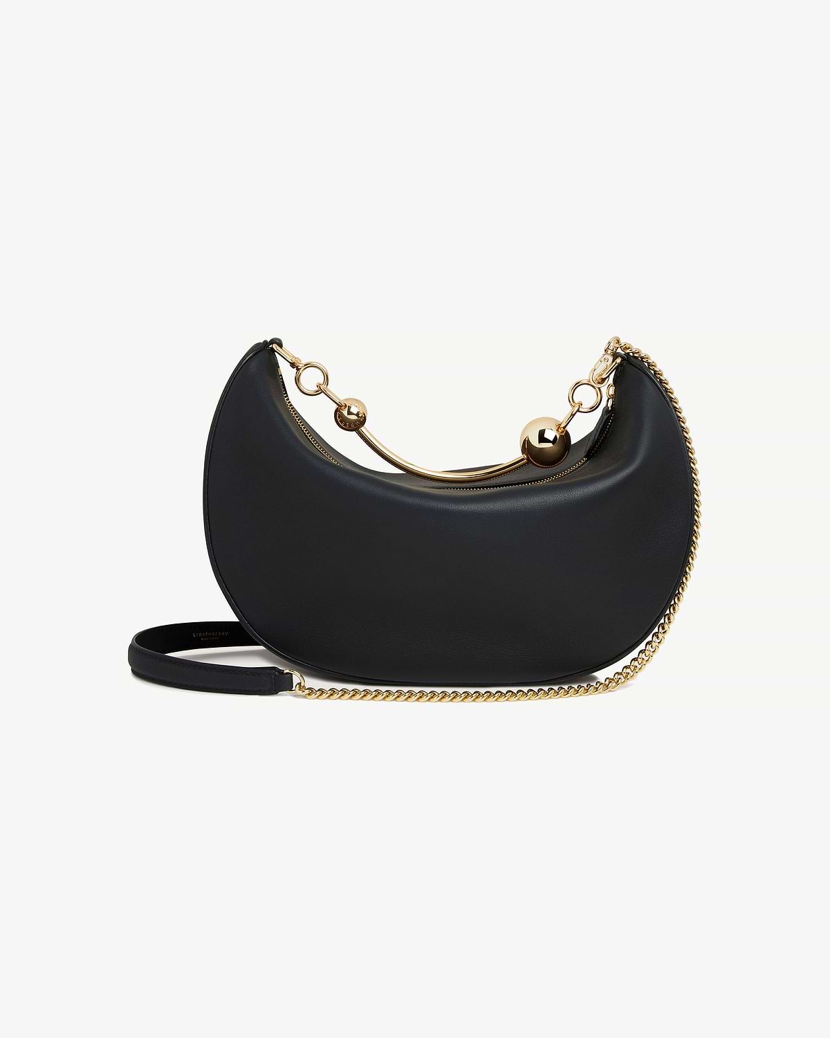 Black crescent-shaped leather bag with gold chain strap and curved handle with ball details.